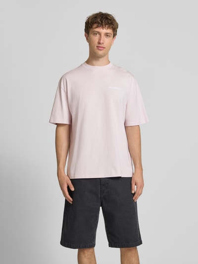 Männermodel trägt Oversized T-Shirt mit Label-Stitching von Pegador aus Baumwoll-Mix in Rosa, Rundhalsausschnitt, Rückenlänge 70 cm, Ganzkörperansicht von vorne.