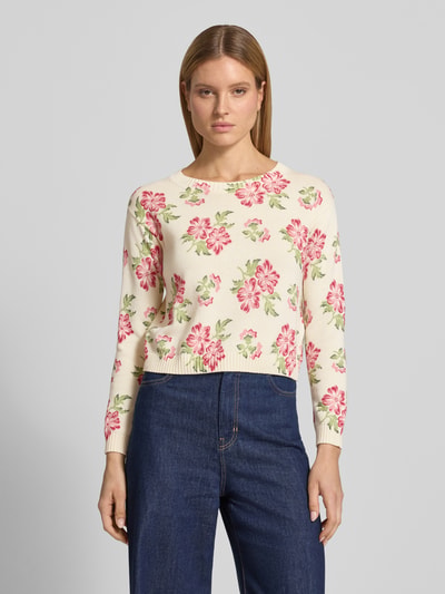 Frauenmodel trägt Boxy Fit Strickpullover aus reiner Baumwolle Modell 'EDITTO' von Weekend Max Mara mit floralem Muster, Strickoptik, Intarsie, Rundhals und gerippten Abschlüssen in Creme mit rosa und grünen Akzenten, Ganzkörperansicht von vorne.