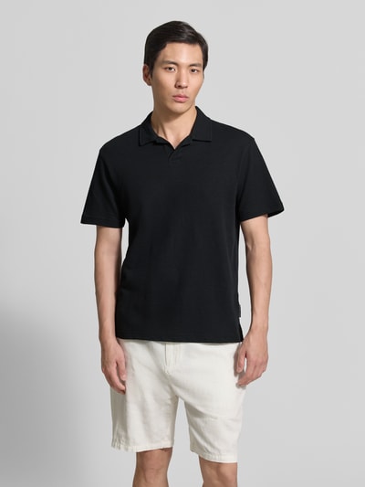 Männermodel trägt Relaxed Fit Poloshirt aus Baumwoll-Mix von Tom Tailor Denim, unifarben schwarz, Piqué-Textur, Ganzkörperansicht von vorne.