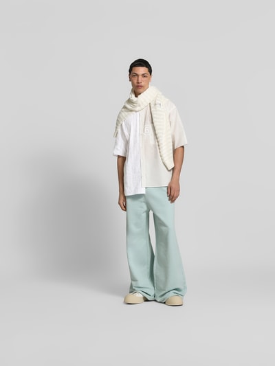 Männermodel trägt Regular Fit Freizeithemd aus Baumwolle von MM6 Maison Margiela, Asymmetrischer-Look, Halbarm, Unifarbenes-Design, Ganzkörperansicht von vorne.