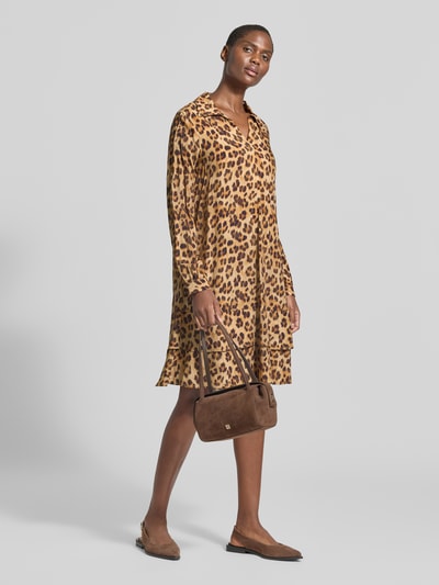 Vrouwenmodel draagt Relaxed Fit jurk uit zuiver viscose van Emily Van den Bergh met animalprint in bruintinten, platte kraag, knielengte, met lange mouwen, ruglengte maat 36: 97 cm, borstwijdte maat 36: 47 cm, mouwlengte maat 36: 63 cm. Ganzkörperansicht von voren.