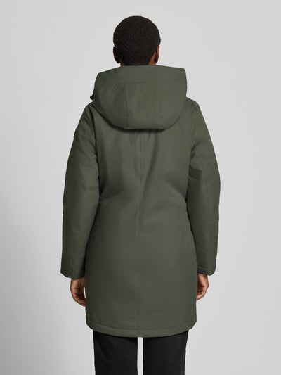 Frauenmodel trägt Parka mit 10.0000mm Wassersäule von G.I.G.A. DX in Olivgrün, glatte Stoffstruktur, Rückenansicht, Ganzkörperansicht Rückansicht. Rückenlänge 88 cm, Schulterbreite 42 cm, Brustweite 49 cm, Ärmellänge 64 cm, Regular Fit, Kapuze, verdeckter Reißverschluss, Eingrifftaschen, Ärmelriegel.