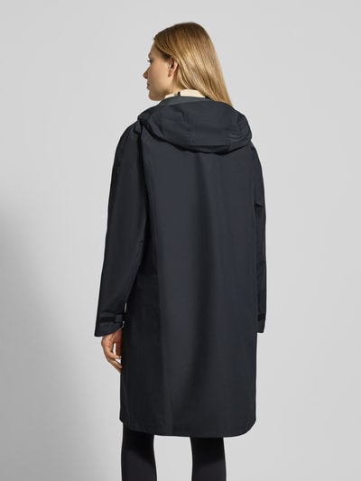 Frauenmodel trägt Mantel mit Zweiwege-Reißverschluss und Kapuze von PEAK PERFORMANCE, Relaxed Fit, dunkle Farbe, Ganzkörperansicht Rückansicht.