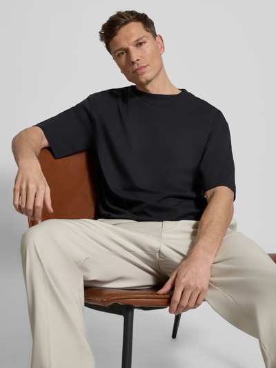 Männermodel trägt Relaxed Fit T-Shirt aus reiner Baumwolle von JAKE*S STUDIO MEN in Schwarz, Rundhalsausschnitt, Halbarm, Nahaufnahme Oberkörper. Herren T-Shirt aus Bio-Baumwolle, Rückenlänge bei Größe M: 65 cm.