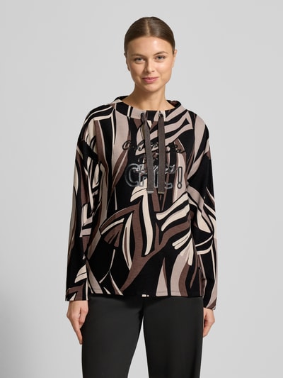 Modelka kobieca ma na sobie 'Sweatshirt mit Tunnelzug' od Betty Barclay, luźny krój, okrągły dekolt, wzór w odcieniach brązu, czerni i beżu, detal z logo, mieszanka wiskozy z domieszką stretchu, widok całej sylwetki z przodu.
