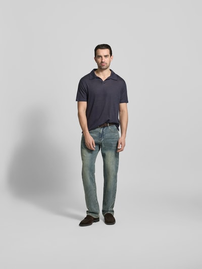 Männermodel trägt Regular Fit Poloshirt aus reinen Leinen von Officine Générale in Dunkelblau, semitransparenter Look, Kurzarm, Ganzkörperansicht von vorne.