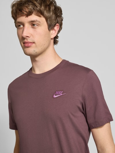 Männermodel trägt T-Shirt mit Label-Stitching von Nike in Lila, reine Baumwolle, Regular Fit, Rundhals, Nahaufnahme Oberkörper.