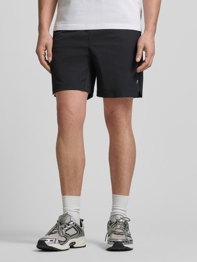 Männermodel trägt Regular Fit Shorts mit Logo-Print von Fabletics, elastischer Bund, schwarzer Farbton, Ganzkörperansicht von vorne.