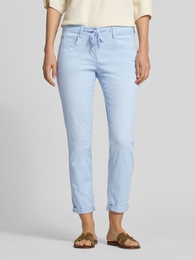 Frauenmodel trägt Tapered Fit Chino aus Baumwoll-Mix von Tom Tailor in Optik: Unifarben, Passform: Tapered-Fit, Slim Leg, Webstruktur, 5-Pocket-Design, Label-Prägung, Bundhöhe: Low-Waist, Länge: Cropped, Knopf und verdeckter Reißverschluss, Ganzkörperansicht von vorne.