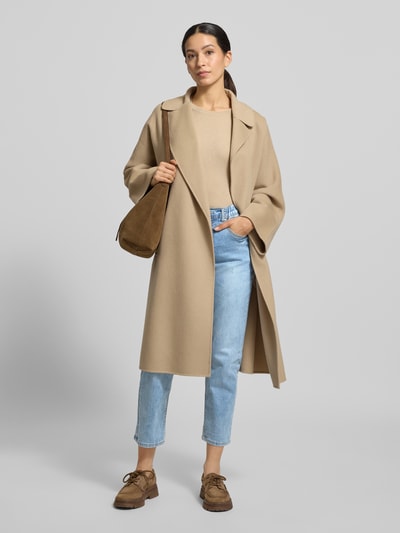 Frauenmodel trägt Jeans mit 5-Pocket-Design von ZABAIONE, hellblau, gerader Schnitt, kombiniert mit beigem Mantel, Ganzkörperansicht von vorne.