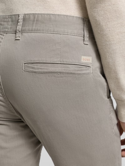 Männermodel trägt Slim Fit Chino aus Baumwoll-Mix Modell 'CHINO_SLIM' von BOSS Orange mit feinem Strukturmuster, Detailaufnahme Rückansicht.