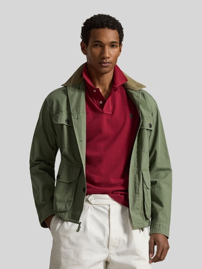 Mannelijk model draagt Regular Fit Poloshirt uit pure katoen van Polo Ralph Lauren, effen rood, logo-detail, piquéstructuur, korte mouw, V-hals, polokraag, korte knoopsluiting, rechte zoom met zijsplitten, voorkant geheel in beeld