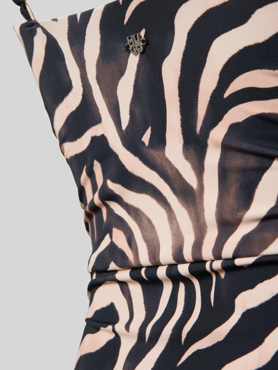Frauenmodel trägt Badeanzug mit seitlichen Raffungen Modell 'FANCY' von HUGO, Optik:Allover-Muster, Animal-Print, Nahaufnahme Oberkörper.