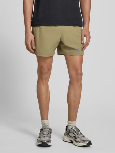 Männermodel trägt Shorts mit elastischem Bund und Label-Print von HALO in Beige, Material-Mix mit Stretch, Nahaufnahme Oberschenkel vorne.