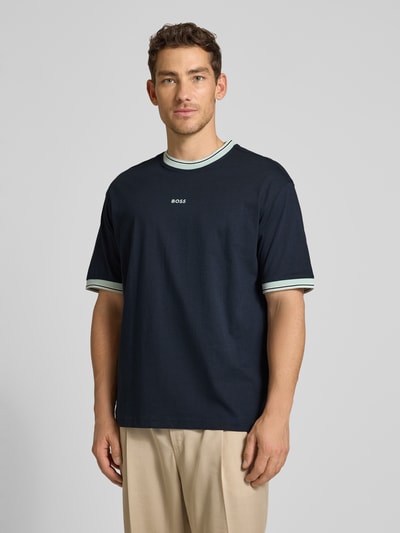 Männermodel trägt Regular Fit T-Shirt aus reiner Baumwolle Modell 'TE_BLOCKS' von BOSS Orange in Dunkelblau mit Rundhals, Label-Stitching-Applikation, Jersey, Ganzkörperansicht von vorne.