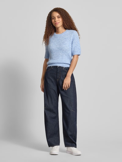Vrouwenmodel draagt Regular Fit Strickpullover mit Woll-Anteil Modell 'STARLA' van ONLY in effen mêlee, korte mouw, ronde hals, geribde zoom, materiaalmix met wol, gebreide structuur, blauw. Ganzkörperaanzicht van voren.