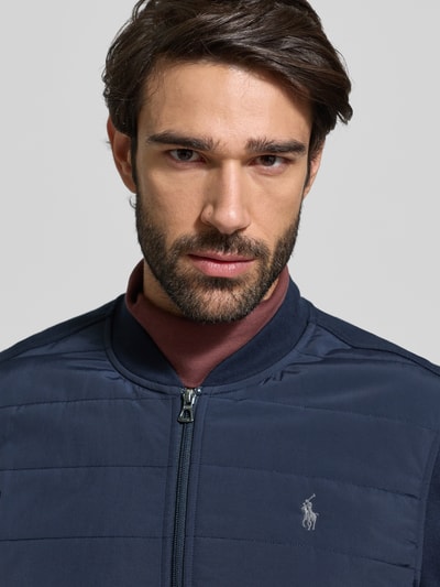 Männermodel trägt Sweatjacke mit gerippten Abschlüssen von Polo Ralph Lauren, Regular-Fit, Stehkragen, Reißverschluss, Label-Stitching, Nahaufnahme Oberkörper.