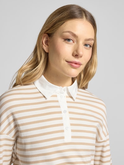 Frauenmodel trägt Regular Fit Poloshirt mit breitem Bund von Marc Cain aus elastischem Baumwoll-Mix, beige-weiß gestreift, Nahaufnahme Oberkörper.