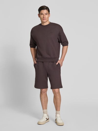 Mężczyzna nosi Relaxed Fit Sweatshirt aus reiner Baumwolle od Lacoste, jednolity kolor, wyhaftowane logo, dzianina dresowa, bawełna, krój relaxed fit, okrągły dekolt, długi rękaw, zakończenie prążkowane. Ganzkörperansicht von vorne.