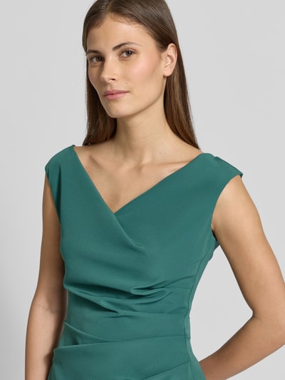 Vrouwenmodel draagt knielange Cocktailjurk met plooien van Vera Mont, materiaalmix met stretch, recht model, V-hals. Nahaufnahme Oberkörper.