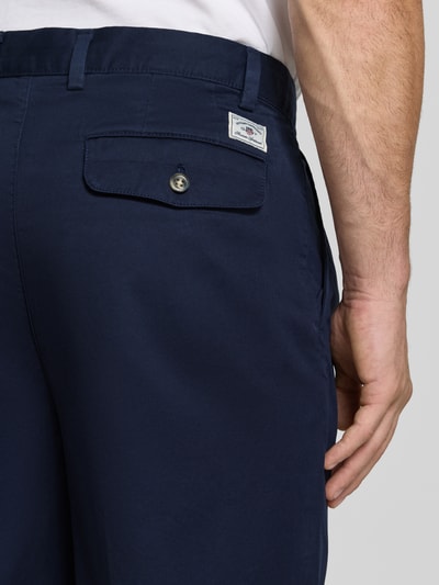 Mężczyzna nosi granatowe chinosy Relaxed Fit Chino aus reiner Baumwolle od GANT, gładka tekstura, detal kieszeni, zbliżenie tylnej części ciała.
