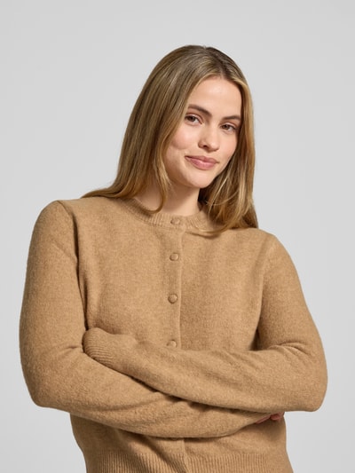 Frauenmodel trägt Cardigan mit Rundhalsausschnitt Modell 'SEEDSUN' von Mango, beige, weiche Textur, Knopfleiste, Regular Fit, Nahaufnahme Oberkörper.