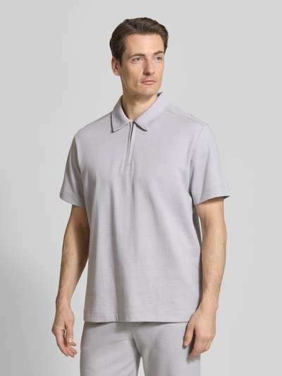 Męski model nosi Regular Fit Poloshirt mit Reißverschluss od Schiesser z mieszanki bawełny, kołnierzyk polo, zamek błyskawiczny, długość tyłu 71 cm w rozmiarze 50, widok całej sylwetki z przodu