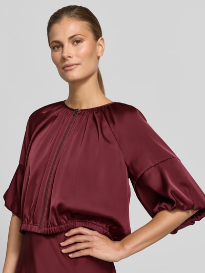 Frauenmodel trägt Cropped Jacke aus Satin mit Reißverschluss von V by Vera Mont in dunklem Rot, Rundhalsausschnitt, glatte Satin-Optik, Rückenlänge bei Größe 36: 45 cm, Nahaufnahme Oberkörper.