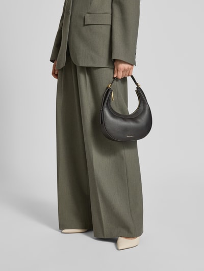 Kobiece model prezentuje torbę na ramię 'Umhängetasche mit Label-Detail' od Coccinelle, czarny kolor, zatrzask, przegródki, detal z logo, detailaufnahme.