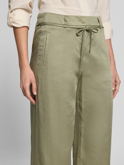 Kobiece modelka nosi oliwkowe Wide Leg Pants mit Bindegürtel Modell 'Meeri bloom' od OPUS, lyocell z bawełną, francuskie kieszenie, szerokość w rozmiarze 36: 40 cm, długość nogawki 68 cm, zbliżenie na górną część ciała.