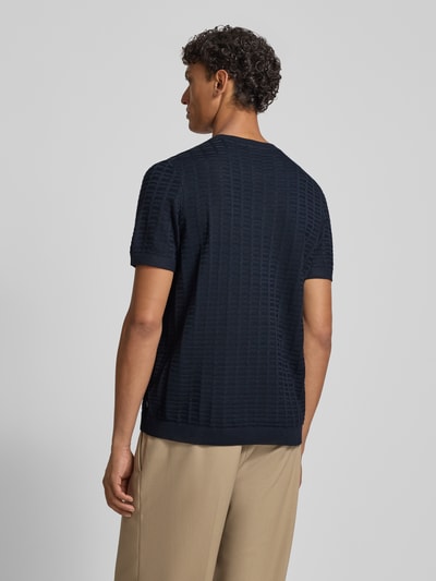 Männermodel trägt T-Shirt mit Label-Detail Modell 'Theor' von JOOP! Collection, dunkelblauer Viskose-Mix, strukturierte Oberfläche, Ganzkörperansicht Rückansicht.
