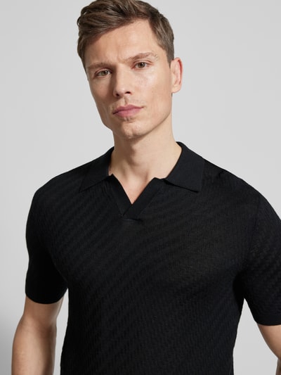 Männermodel trägt schwarzes Slim Fit Poloshirt mit Lyocell-Anteil von Emporio Armani, Strick-Optik, Nahaufnahme Oberkörper.