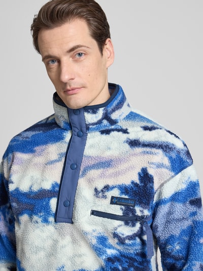 Männermodel trägt Regular Fit Pullover mit Logo-Patch von Columbia in fließ-Optik mit Brusttasche und Druckknopfleiste, Nahaufnahme Oberkörper.