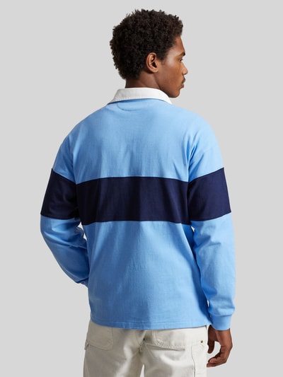 Männermodel trägt Regular Fit Poloshirt aus reiner Baumwolle von Polo Ralph Lauren in Hellblau mit dunkelblauem Streifen, unifarben, Piqué-Textur, Langarm, Label-Schriftzug, Ganzkörperansicht Rückansicht.
