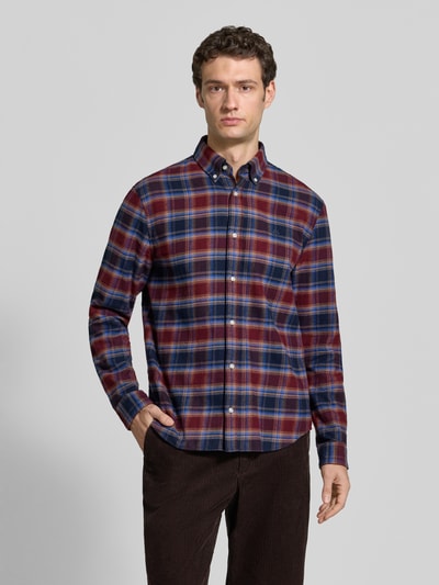 Męski model nosi Regular Fit Freizeithemd mit Button-Down-Kragen od MCNEAL, wzór na całej powierzchni, wyhaftowane logo, listwa guzikowa, długość tyłu w rozmiarze M 75 cm, szerokość ramion w rozmiarze M 47 cm, długość rękawów w rozmiarze M 66 cm, kolor bordowy i granatowy, tekstura miękka, widok na całe ciało z przodu.