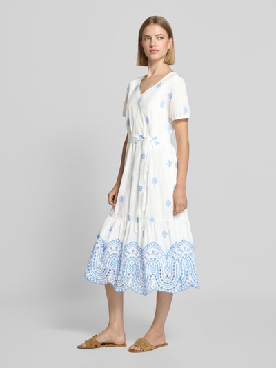 Frauenmodel trägt Midikleid mit Lochstickerei und Bindegürtel von MORE & MORE, A-Linie, Allover-Look, weiße Baumwolle mit blauen Akzenten, Ganzkörperansicht von vorne.