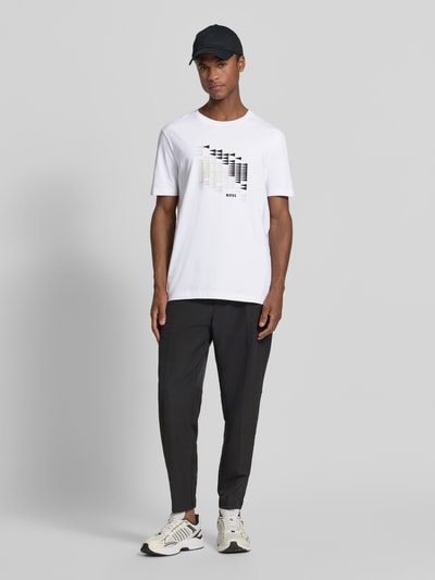 Męski model nosi Relaxed Fit T-Shirt aus Baumwoll-Mix Modell 'TS_NETWORK FLAG' von BOSS Green, biała i czarna grafika, Ganzkörperansicht von vorne.