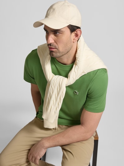 Męski model nosi Regular Fit Poloshirt aus reiner Baumwolle od Lacoste, efekt: jednolity kolor, wyhaftowane logo, okrągły dekolt, krótki rękaw, bawełna; widok całej sylwetki z przodu.