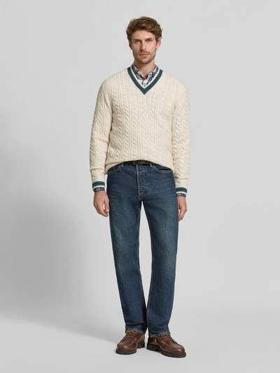 Männermodel trägt Strickpullover mit Woll-Anteil von MCNEAL, Woll-Mix, V-Ausschnitt, Zopfmuster, cremefarben, Ganzkörperansicht von vorne.