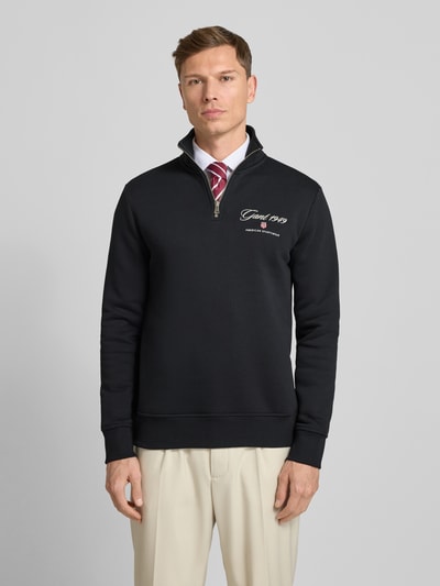 Männermodel trägt Sweatshirt mit Stehkragen und Reißverschluss von Gant, schwarz, Baumwoll-Mix, Regular Fit, Ganzkörperansicht von vorne.
