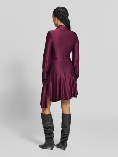 Frauenmodel trägt Knielanges Kleid aus Viskose-Mix von Rabanne in dunklem Weinrot, glänzende Textur, taillierte Passform, Umlegekragen und Langarm, Produktlänge 93 cm, Brustweite 40 cm, Ärmellänge 71 cm, Ganzkörperansicht Rückansicht.
