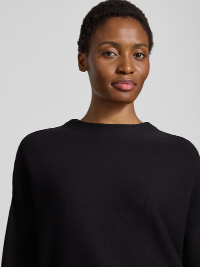 Frauenmodel trägt schwarzen Loose Fit Pullover aus reiner Baumwolle Modell 'MERINAA' von ARMEDANGELS, Nahaufnahme Oberkörper.