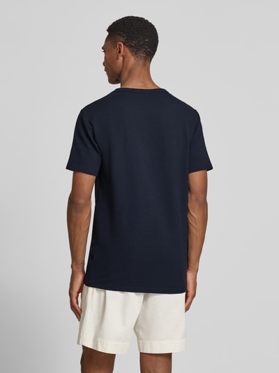 Männermodel trägt Regular Fit T-Shirt aus Baumwoll-Mix Modell 'SANDER' von SELECTED HOMME in Dunkelblau, Seersucker-Struktur, Ganzkörperansicht Rückansicht.