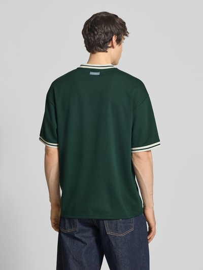 Männermodel trägt Boxy Fit T-Shirt aus reiner Baumwolle Modell 'LES' von Only & Sons in Optik: Unifarben mit Label-Print, Ganzkörperansicht Rückansicht.