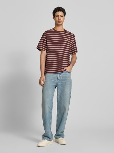 Männermodel trägt Strukturiertes T-Shirt mit Logostickerei auf der Brust von REVIEW in Reine Baumwolle, Gerader-Schnitt, Rundhalsausschnitt, Label-Stitching und Lochstickerei, Strukturmuster, Rückenlänge bei Größe M: 70 cm, braun-weiß gestreift, Ganzkörperansicht von vorne.