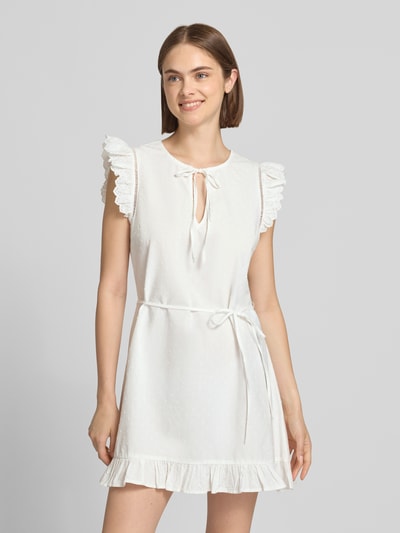 Frauenmodel trägt weißes, kurzärmeliges Blusenkleid mit Rüschen, strukturierter Baumwollstoff, Gerades Blusenkleid aus reiner Baumwolle Modell 'PCGOLDIE' von PIECES, Ganzkörperansicht von vorne, Damen Blusenkleid von PIECES.