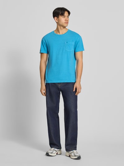 Männermodel trägt T-Shirt aus Baumwoll-Leinen-Mix mit Brusttasche von Superdry in Blau, Regular Fit, Rundhalsausschnitt, Ganzkörperansicht von vorne.