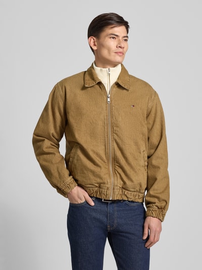 Männermodel draagt Regular Fit Bomberjacke aus reiner Baumwolle van Tommy Hilfiger in effen beige, denimstructuur, zijzakken, lang mouw, elastische boorden, logo detail, volledige voorkant weergave.