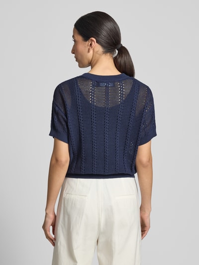 Frauenmodel trägt Relaxed Fit Strickshirt aus Baumwoll-Mix Modell 'LUX LIGHT' von Vero Moda, Optik: Unifarben, Lochstrickmuster, Rundhals, Kurzarm, Ärmelabschluss gerippt, Rumpfabschluss gerippt, Materialverarbeitung: Lochstrick, Farbe Dunkelblau, Textur leicht transparent, Ganzkörperansicht Rückansicht.