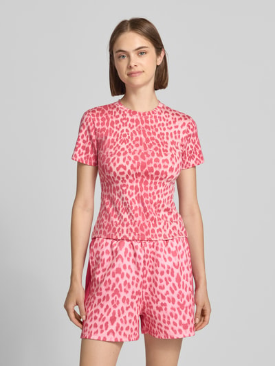 Frauenmodel trägt Slim Fit T-Shirt im Allover-Look Modell 'Joy' von OH APRIL in Rosa mit Label-Stitching, Nahaufnahme Oberkörper.